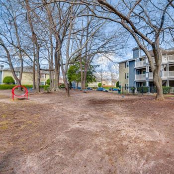 a playground in front of an apartment building with trees at Palmetto Place Apartments, Taylors, SC, 29687